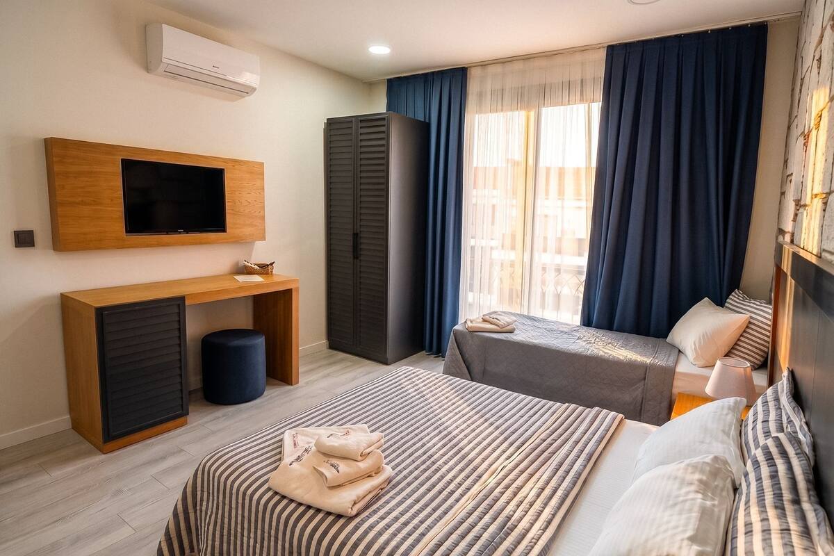 Ein Hotelzimmer mit Bett, Schreibtisch, Fernseher und Kleiderschrank.