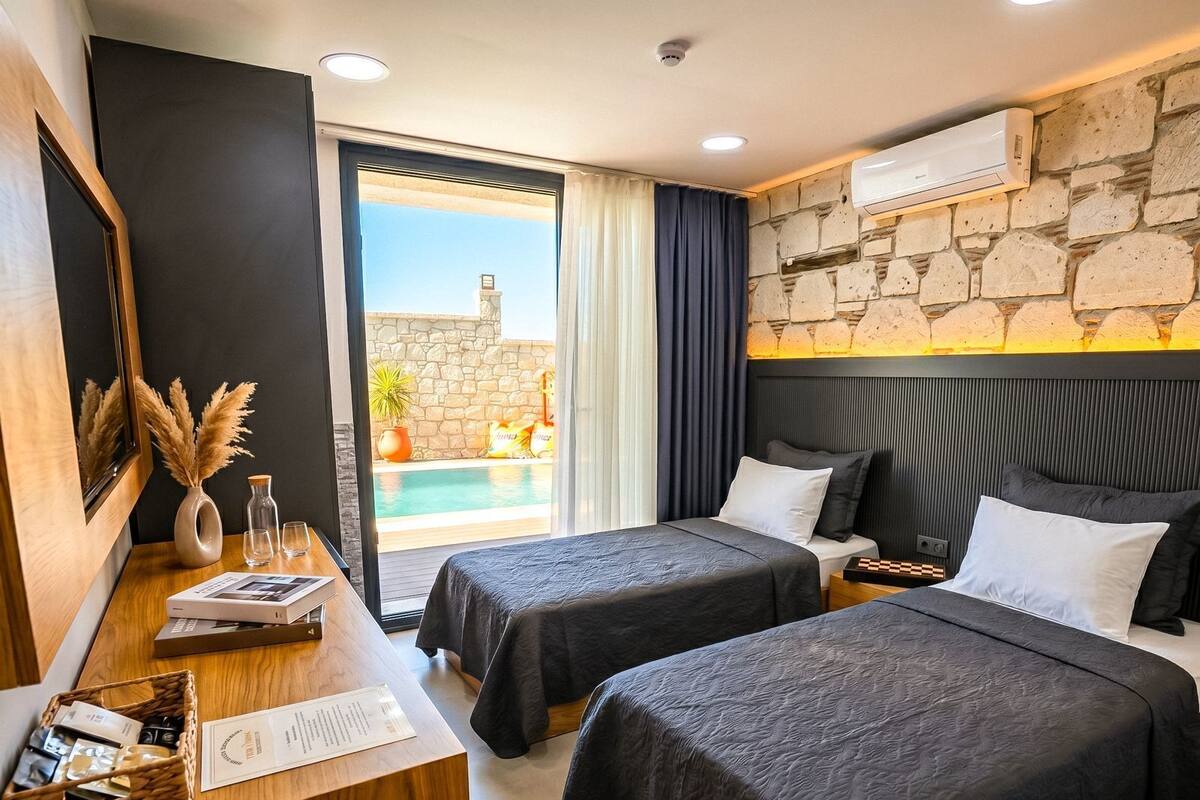 Ein Hotelzimmer mit zwei Betten, einem Schreibtisch mit Korb, einem Spiegel und Blick auf einen Pool.