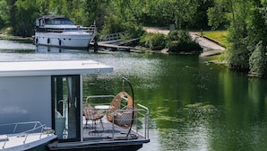 Ein Boot mit überdachter Deck und zwei Korbstühlen sowie einem kleinen Tisch.