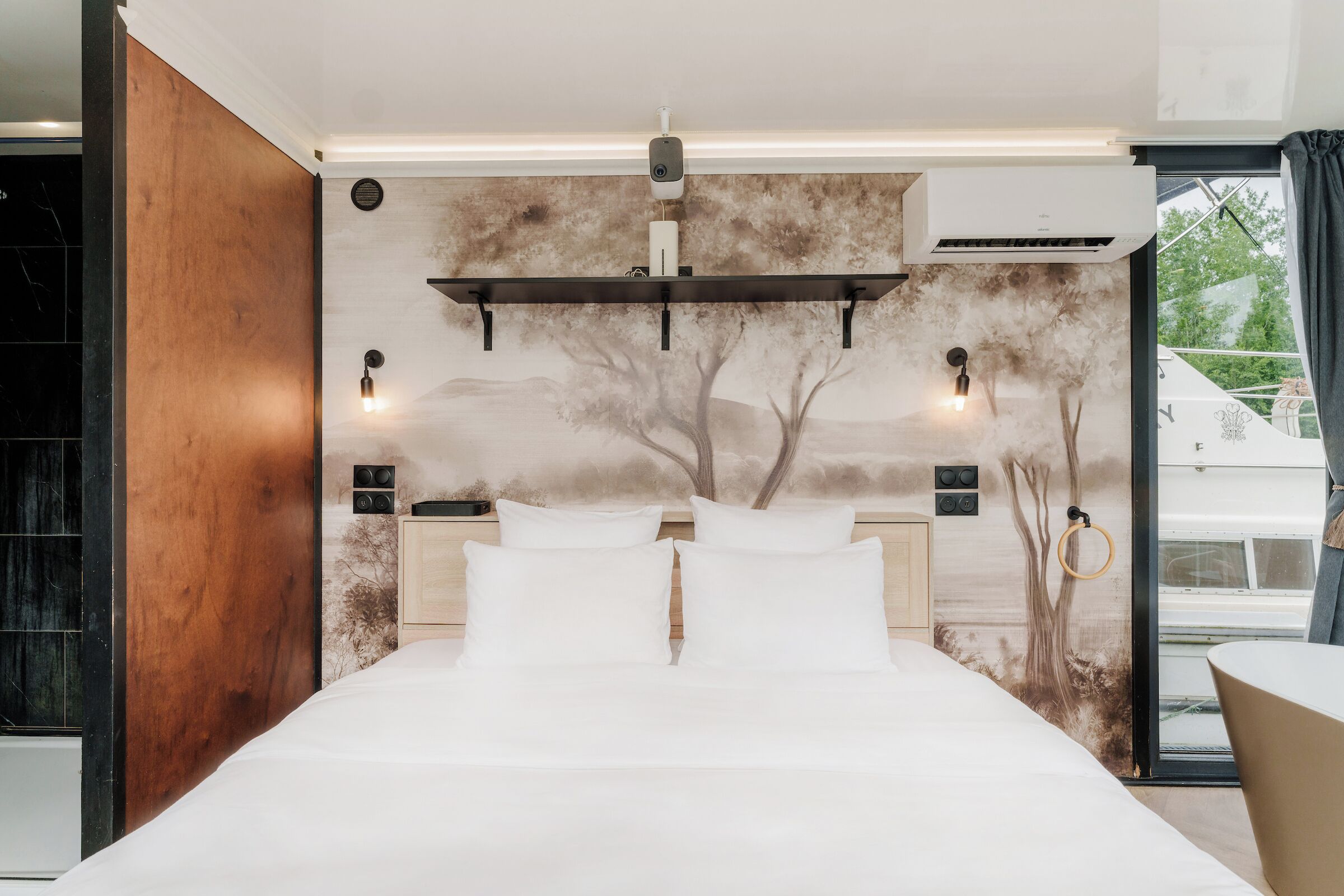 A modern bedroom with a large bed, a wooden accent wall, and a mural of trees.