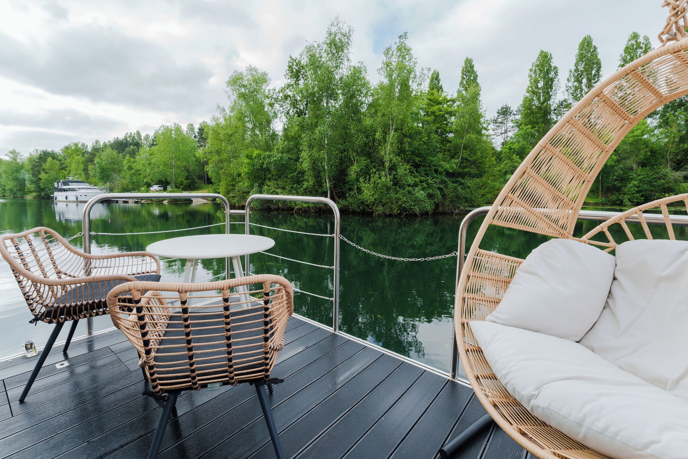 A deck with wicker furniture and a view of a river and trees.