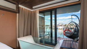 Ein modernes Zimmer mit einem verglasten Balkon, einem Hängesessel und Blick auf einen Pool.