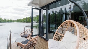 Eine moderne Terrasse mit Korbmöbeln mit Blick auf einen See.