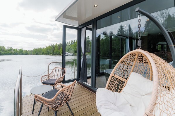 Una terraza moderna con mobiliario de mimbre que da a un lago.