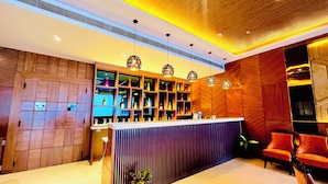 A reception area with a wooden reception desk, shelves with bottles, and a potted plant.