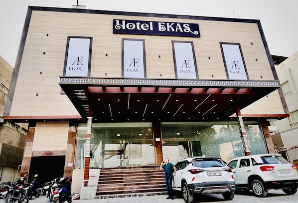 Hotel EKAS with a modern facade, a covered entrance, and parked vehicles.