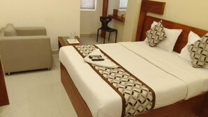 A hotel room with a bed, a sofa, and a small table with a pitcher. - 4 U BUSINESS CLASS (Chennai)