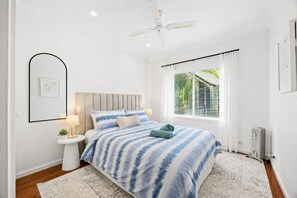 A bedroom with a bed, bedside tables, a ceiling fan, a window with blinds, and a radiator. - Horizon Loft by Ready Set Stay (Cowes)