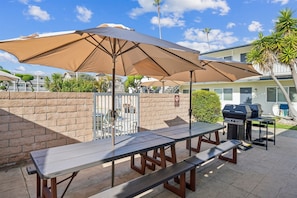 Une terrasse extérieure avec des tables de pique-nique et des barbecues.
