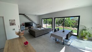 A modern living room with a sofa, TV, and a dining area with a table and chairs. - Beautiful Villa Moderne in Marseille close to all tourist attractions (Unknown)