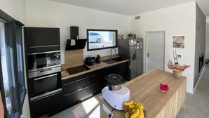 A modern kitchen with built-in appliances, a large window, and a flat-screen TV. - Beautiful Villa Moderne in Marseille close to all tourist attractions (Unknown)