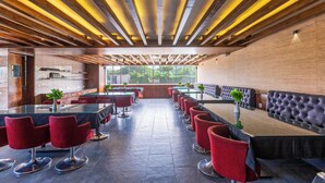 Ein modernes Restaurant mit einem langen Gemeinschaftstisch, roten Stühlen und einer Bar.