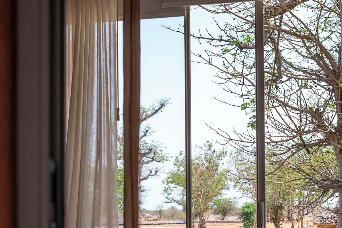 Quarto com uma grande porta de vidro deslizante que dá para uma área externa com lago e árvores.