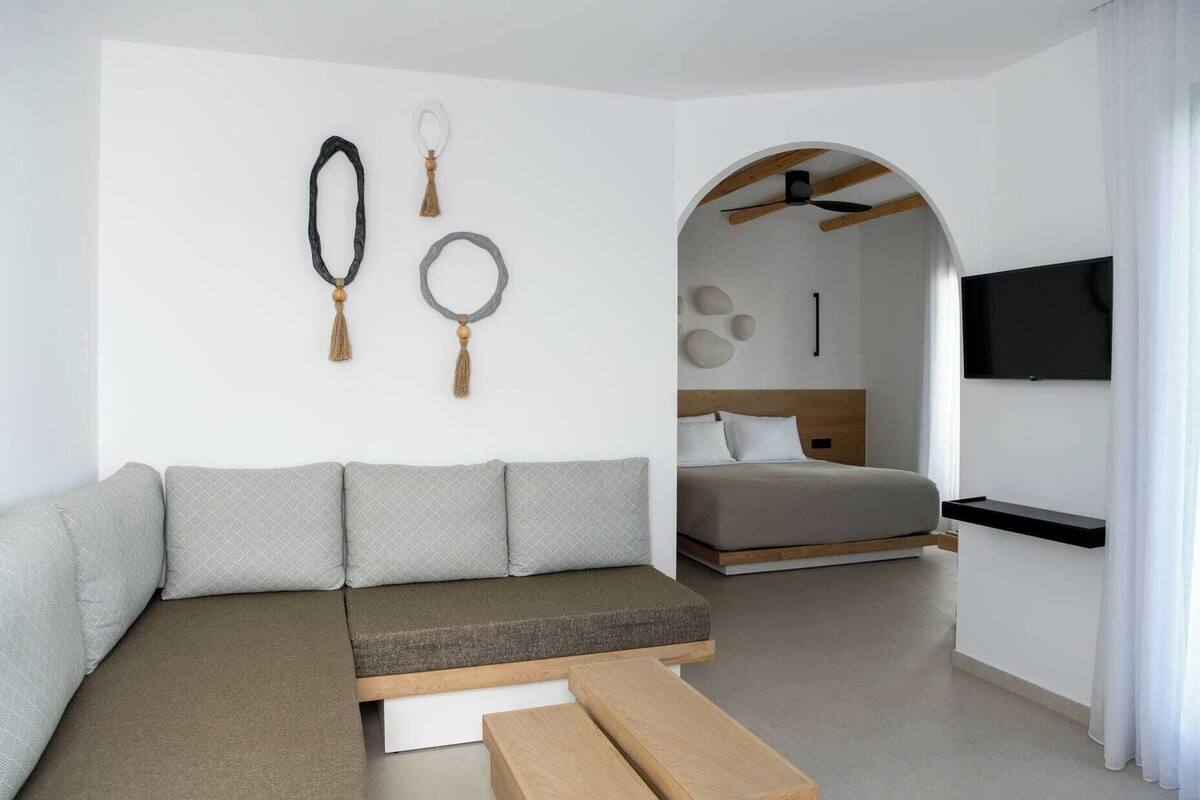 Ein modernes Schlafzimmer mit einer Couch, einem Bett, einem Fernseher und einem Deckenventilator.