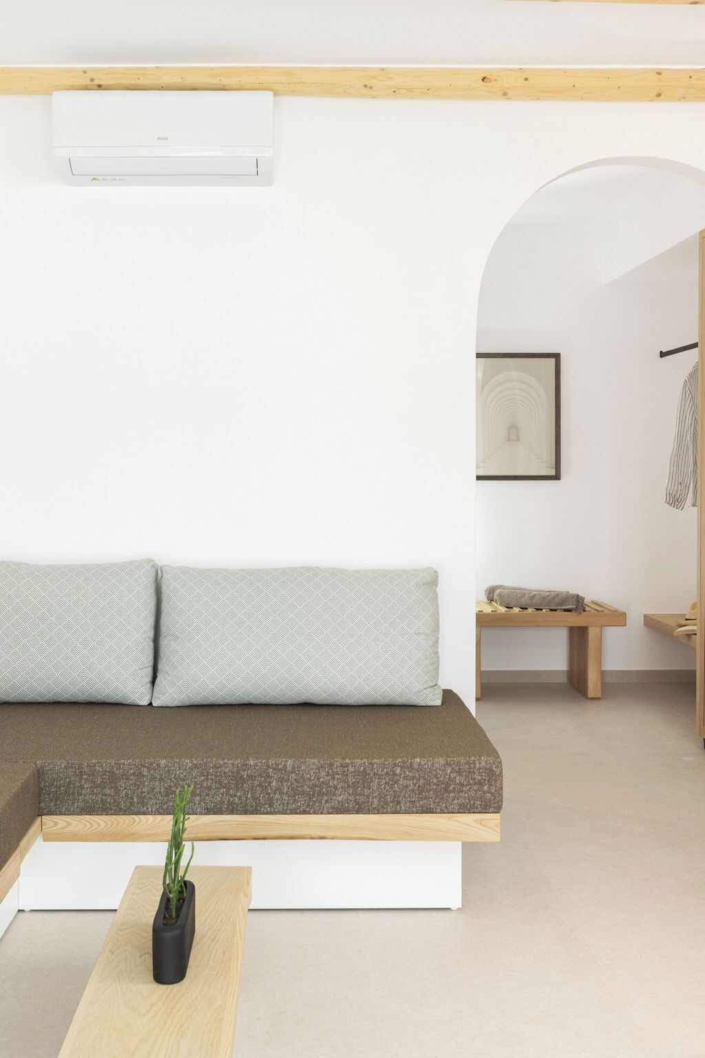 A modern living room with a sectional sofa, a small wooden table with a plant, and a framed picture on the wall.
