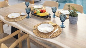 An outdoor dining area with a pool, stone walls, and lounge chairs. - Kalea Suites (Milos)