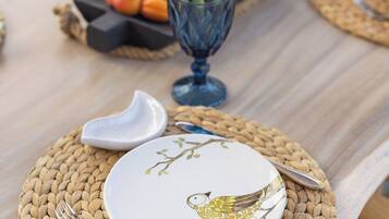 Una mesa de comedor dispuesta con individuales, platos, cubiertos y un frutero.