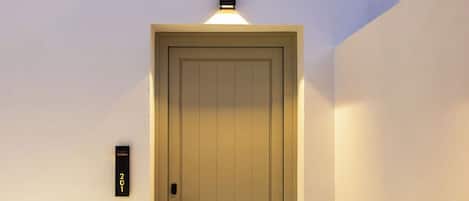 A door with a keypad lock, a wall-mounted light above it, and a room number sign.
