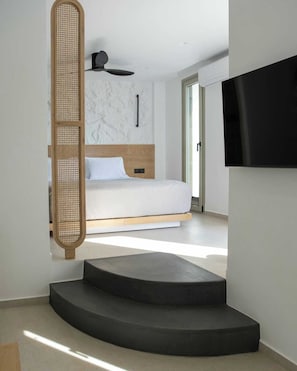 Una camera da letto moderna con un letto, una ventola a soffitto e un televisore montato a parete.