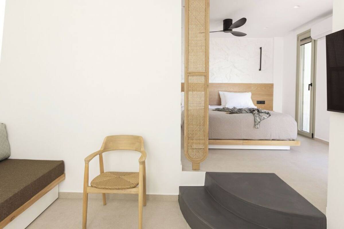 Ein modernes Schlafzimmer mit einem Bett, einem Sessel, einer Couch und einem Deckenventilator.