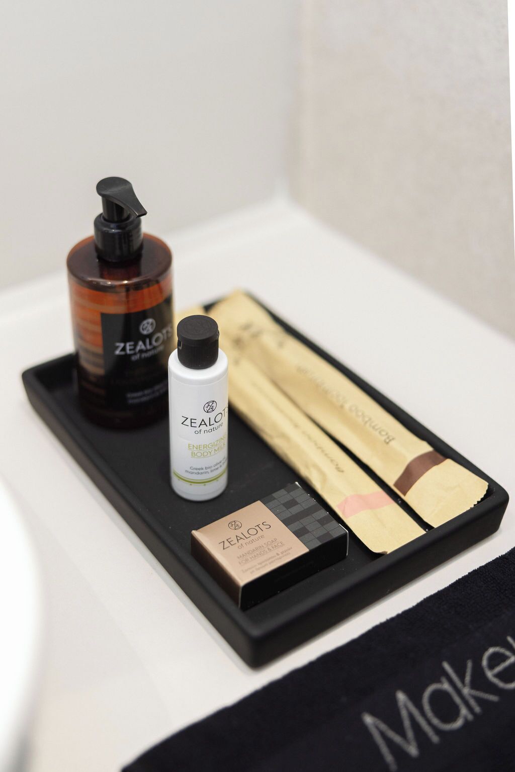 A tray with a bottle of ZEALOTS body wash, a bottle of ZEALOTS energizing body mist, and a box of ZEALOTS mandarin soap.
