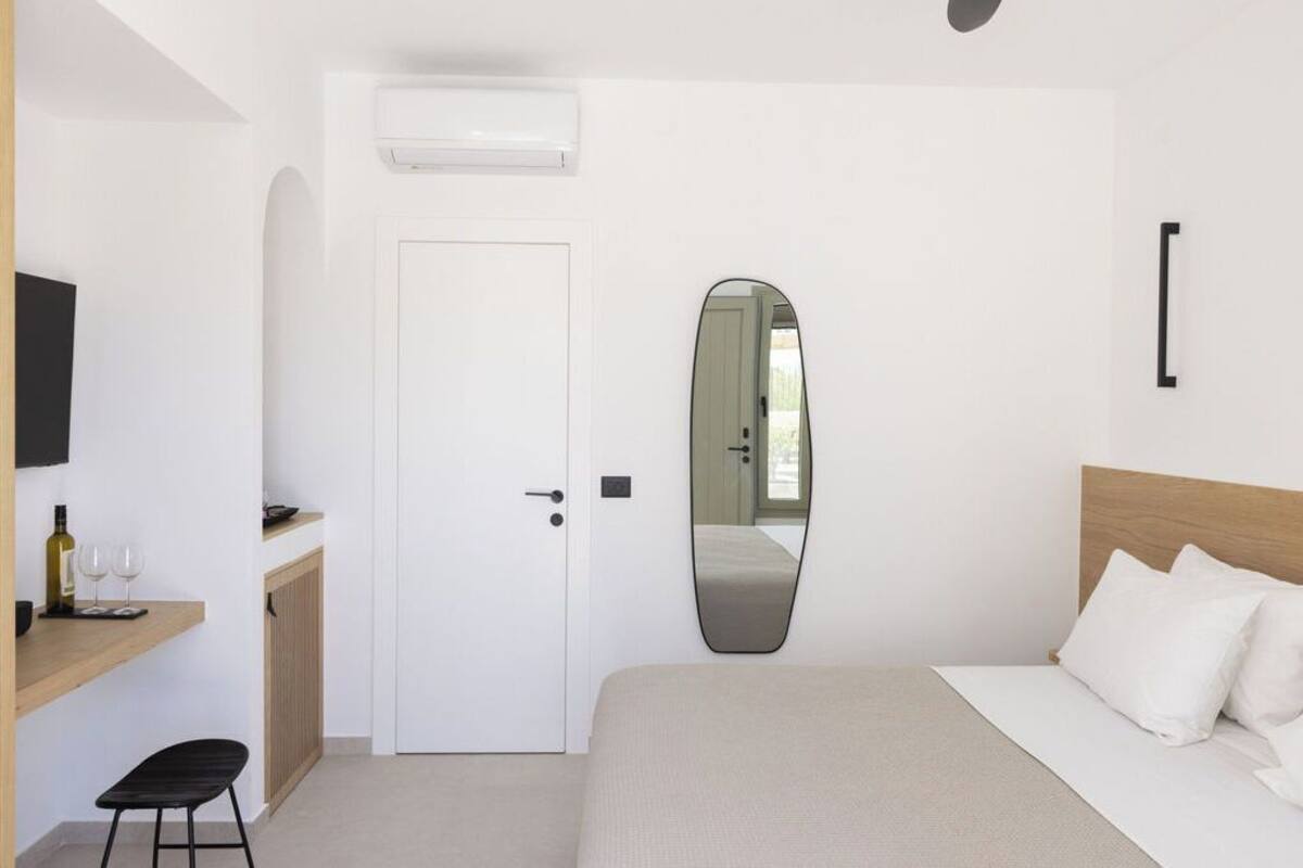 Ein Schlafzimmer mit Bett, Nachttisch, Spiegel und Tür.