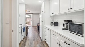 A modern kitchen with white cabinets, a built-in microwave, and a coffee maker.