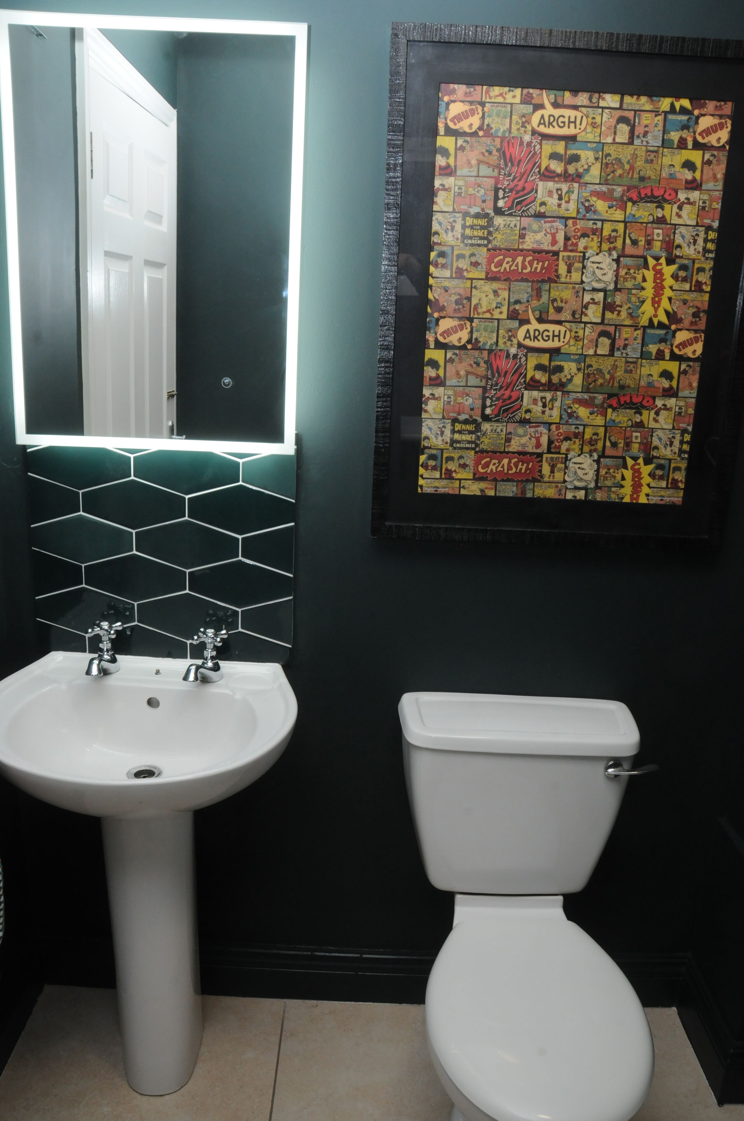 A bathroom with a white sink, a toilet, and a wall-mounted mirror.