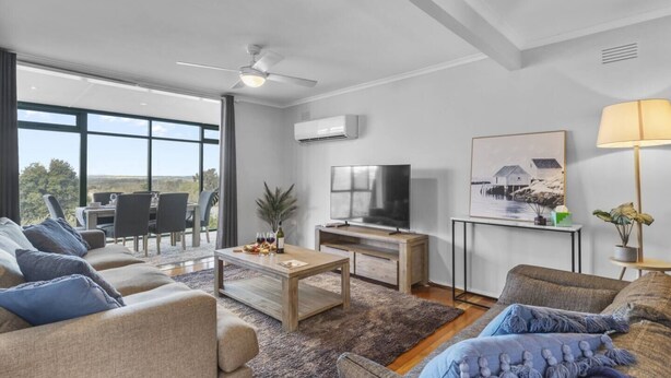Een moderne woonkamer met een bank, salontafel, televisie en een eethoek met stoelen en een tafel.