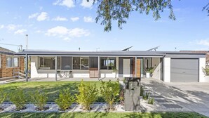 Een modern huis met twee verdiepingen, een overdekte patio, een garage en een verzorgd gazon.