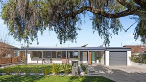 Une maison moderne à deux étages, dotée d’un patio couvert, d’un garage et d’une pelouse bien entretenue.