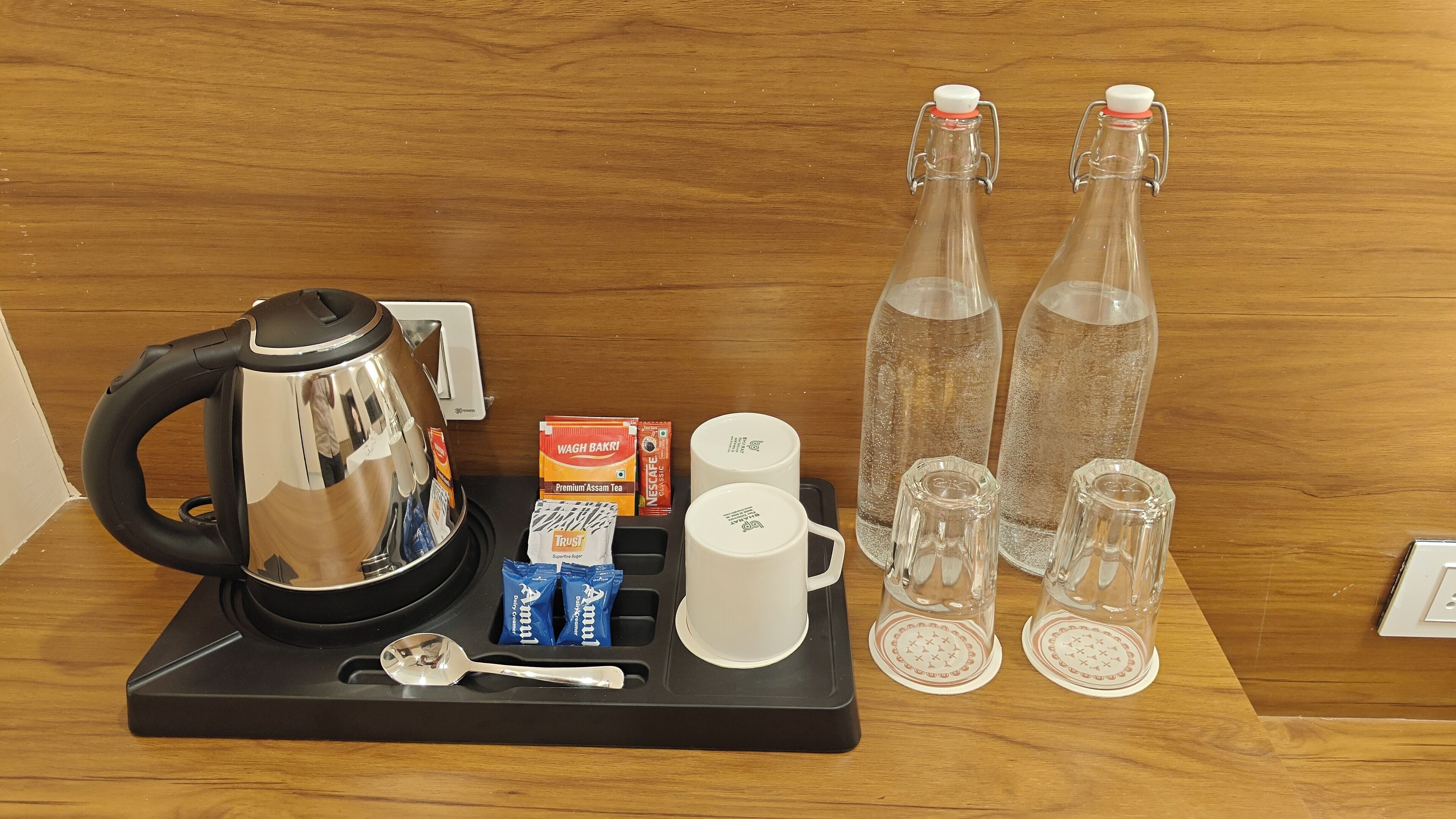 A coffee station with a kettle, cups, tea bags, and sugar packets.