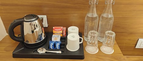 A coffee station with a kettle, cups, tea bags, and sugar packets.