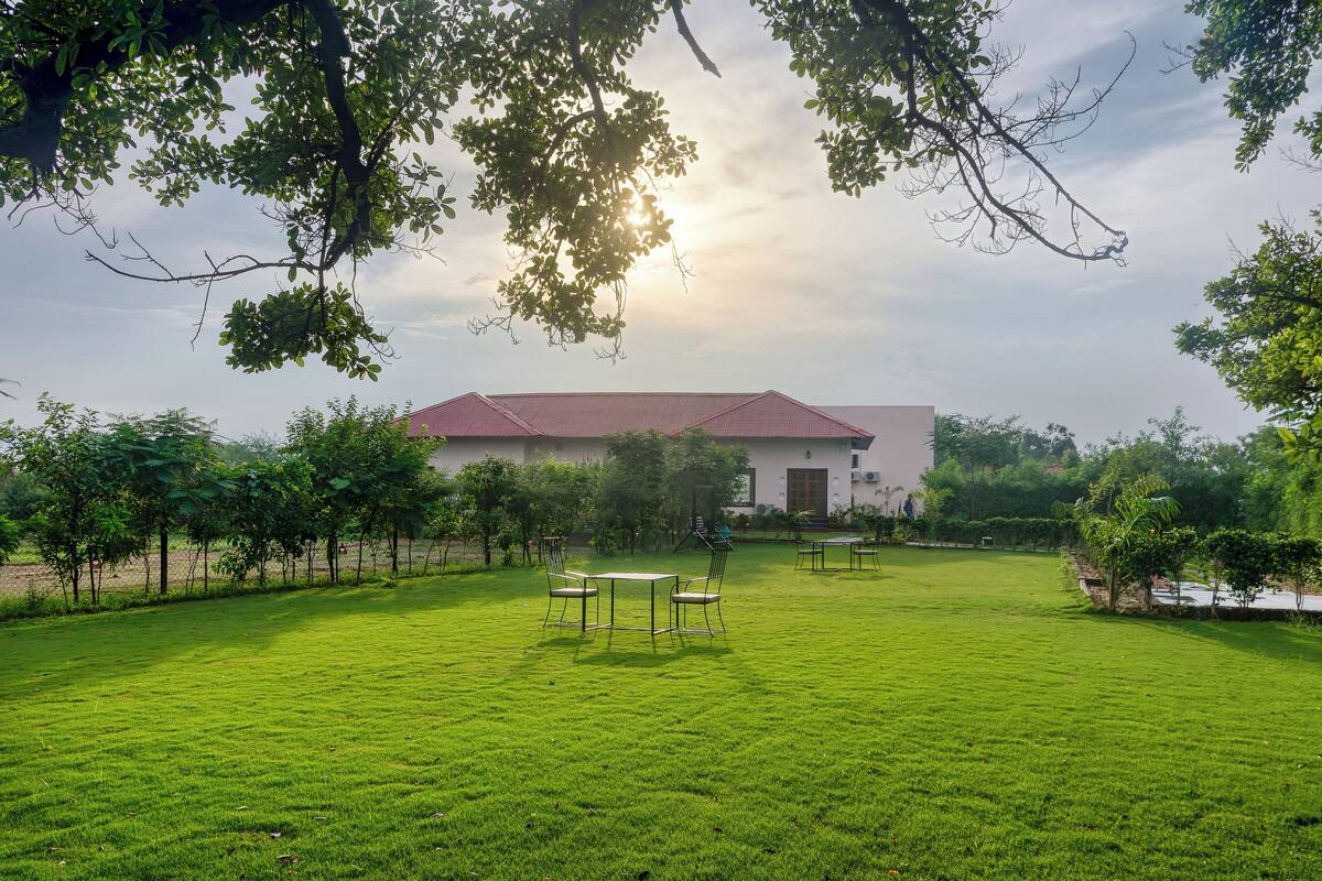A grassy courtyard with a building in the background, surrounded by trees and a clear sky.