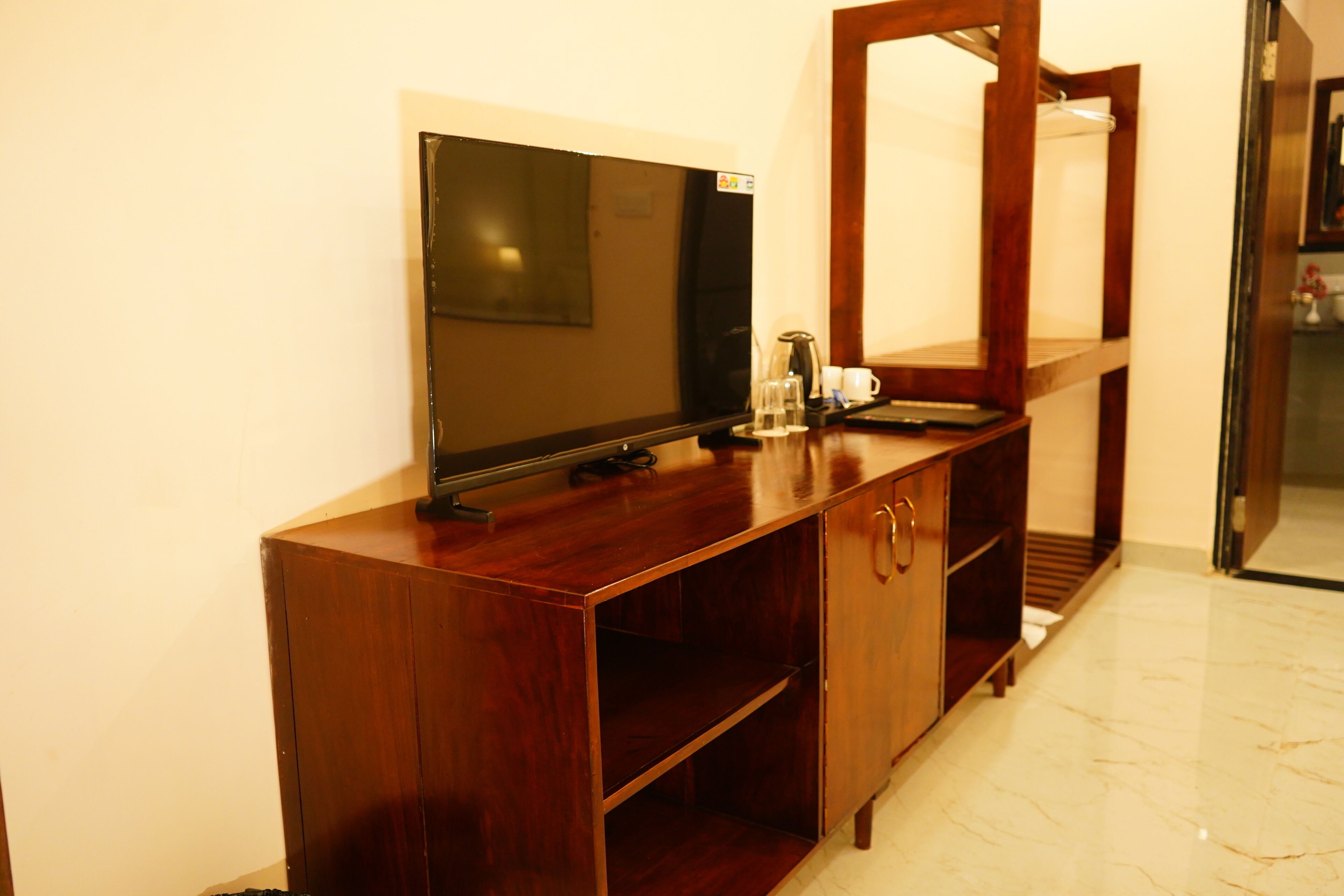 Un mueble de televisión de madera con televisor de pantalla plana, cafetera y espejo.