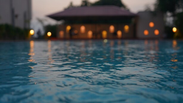 A swimming pool with a blurred background of a building with multiple lights.