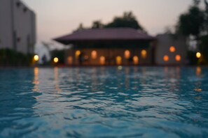 A swimming pool with a blurred background of a building with multiple lights. - Sundervan Vilas Ranthambore (Sawai Madhopur)