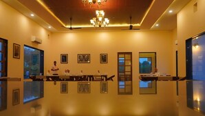 A spacious room with a long table, framed pictures on the walls, and a chandelier.
