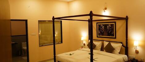 A four-poster bed with a wooden frame, a bedside table with a lamp, and a framed picture on the wall.