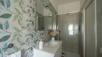 Ein Badezimmer mit Dusche, Waschbecken und Spiegel.