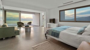 Une chambre moderne avec un grand lit, une télévision et une vue sur la mer.