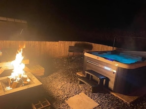 A hot tub and a fire pit in an outdoor setting.