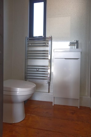 A bathroom with a toilet, a stainless steel towel rail, and a white sink.