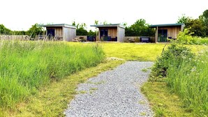 A rural property with three wooden cabins, a gravel path, and surrounding greenery. - Bristol Escape Cabin With Stunning Views (Bristol)