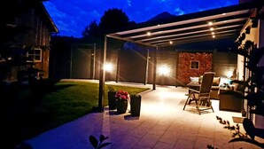 An outdoor patio area with a covered seating area, a fire pit, and a stone wall. - Vacation home TraunseeStrand EXKLUSIV in lakeside location incl. spacious garden (Ebensee)