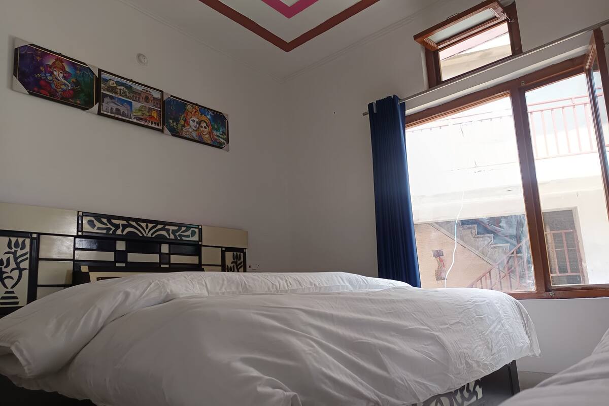 Quarto com cama, janela com cortinas e obras de arte nas paredes.