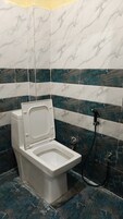 Un baño con inodoro blanco, ducha y pared con diseño de mármol.