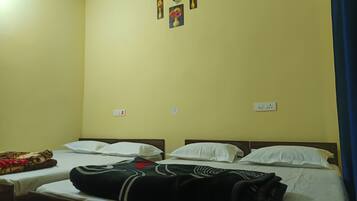 Una habitación con dos camas, cada una con almohadas blancas y una manta negra. Hay dos enchufes en la pared y un pequeño cuadro enmarcado sobre las camas.