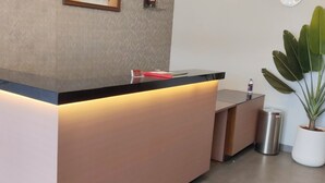 A reception desk with a modern design, a trash can, and a potted plant. - Hotel Sara Executive (Sawardari)