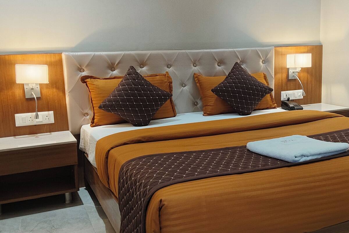 A hotel room with a large bed, two nightstands, and a wooden headboard.